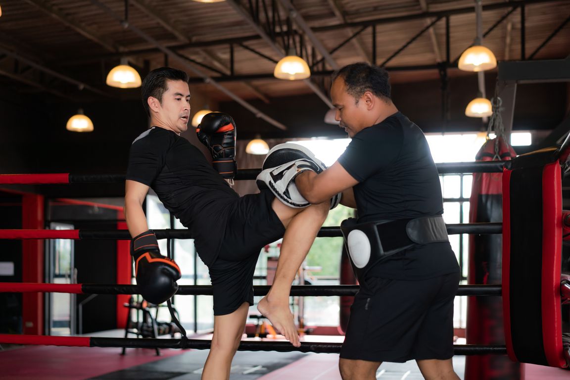 Atleta che esegue un calcio circolare sui colpitori di Muay Thai