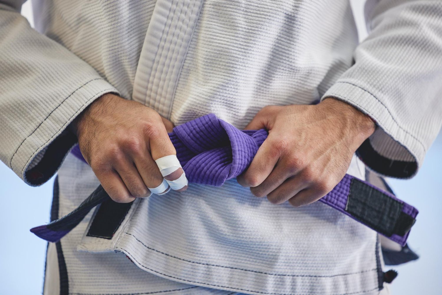 BJJ practitioner tying a purple belt before training