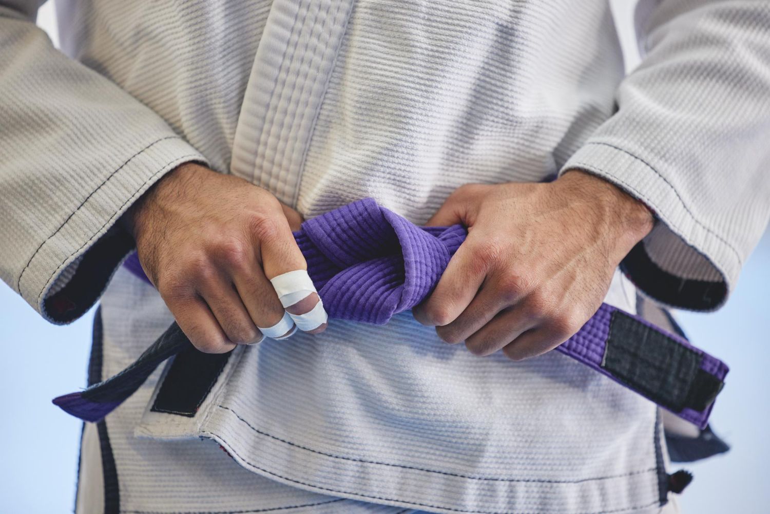 BJJ practitioner tying a purple belt before training